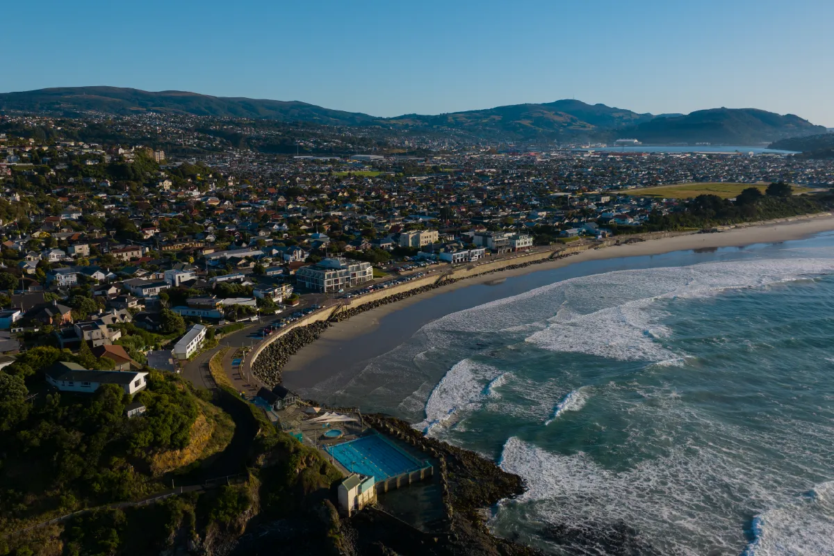 High-angle coastal view of St Clair Beach and Saltwater Pool in Dunedin, a stunning backdrop for outdoor wedding videography.