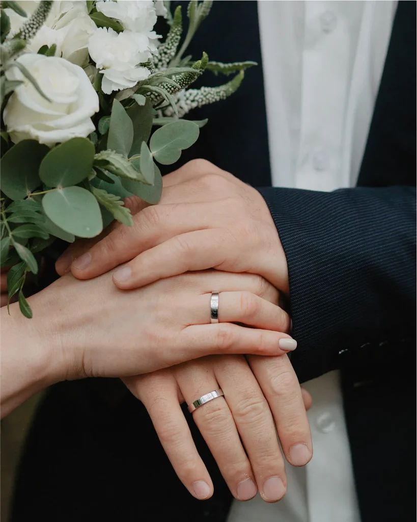 Close-up of wedding rings and joined hands, Vowly Wedding Video Production New Zealand.